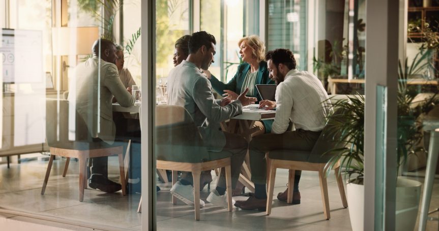 Menschen sitzen an einem Tisch in der Arbeit und reden